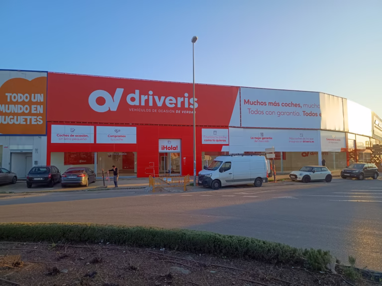 Fachada de un establecimiento comercial con rótulo rojo de gran formato